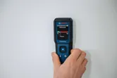 Une personne utilise un humidimètre pour matériaux pour vérifier les niveaux d’humidité sur un mur.