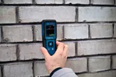 Une personne mesure l’humidité des murs à l’aide d’un humidimètre pour matériaux.