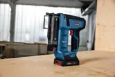 Pistolet à clous sans fil debout sur une table en bois dans un atelier.