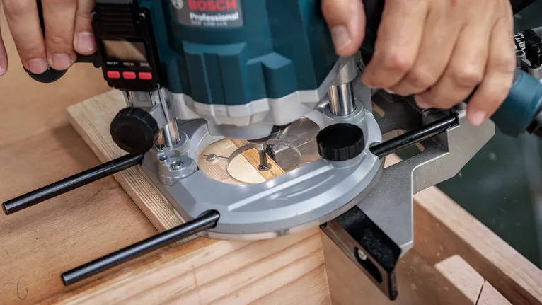 Une personne utilise une défonceuse électrique pour couper le bord d'une planche de bois.
