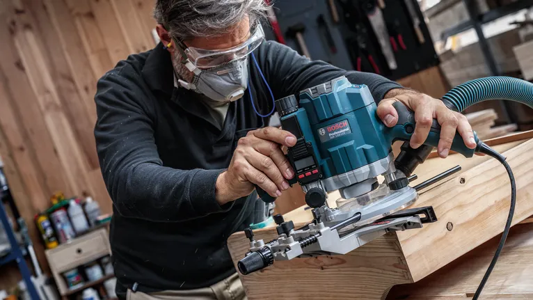 Une personne portant un équipement de sécurité utilise un outil électrique pour façonner le bois dans un atelier.