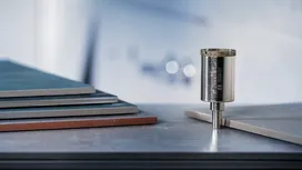 Foret diamanté dressé verticalement à côté de carreaux de céramique empilés.