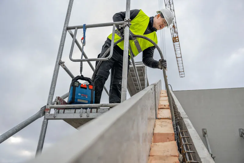 Personne portant un équipement de sécurité travaillant sur un échafaudage sur un chantier de construction.