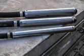 Trois vibrateurs à béton reposent sur une surface de construction.