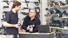 Deux hommes discutent devant un comptoir, outils Bosch Professional en arrière-plan.