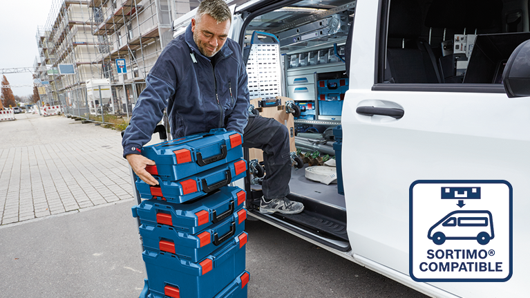 Un homme soulève des boîtes Bosch bleues près d'un véhicule utilitaire.