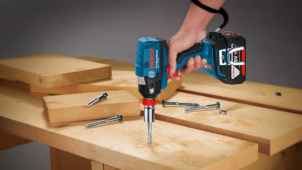 Une perceuse visseuse Bosch Professional est utilisée sur des planches en bois.