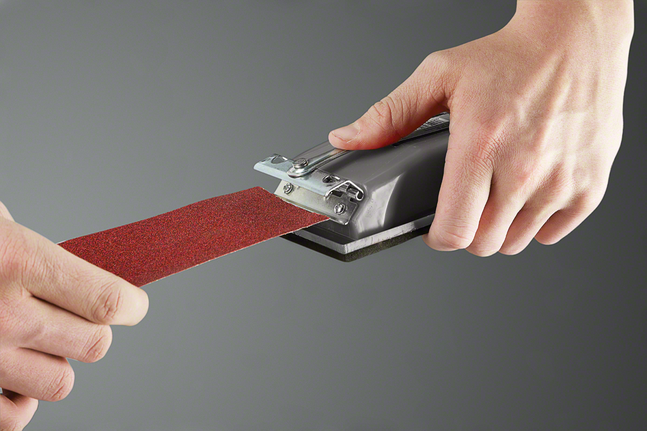Person attaches sandpaper sheet to a hand sanding tool.