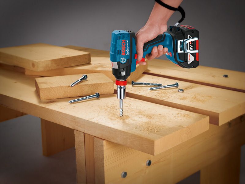 Person using a cordless impact driver to fasten a screw into wooden boards.
