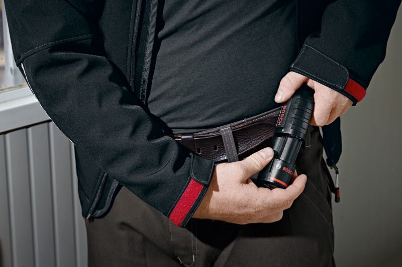 Person placing a cordless flashlight into their belt holster.
