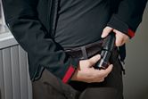 Person placing a cordless flashlight into their belt holster.