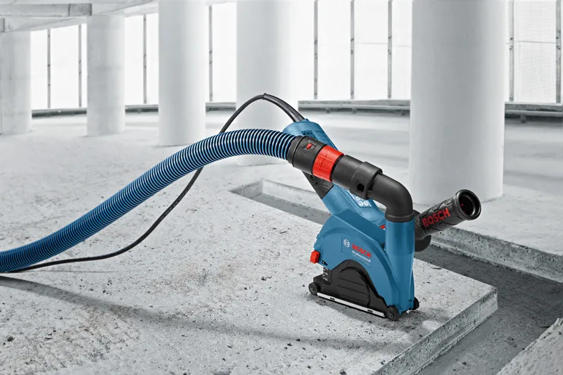 Wall chaser with dust extraction hose is cutting a groove in a concrete floor.