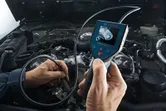 A person uses an inspection camera to examine an engine.