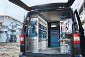 Organized van interior with stacked toolboxes and power tools beside a construction site.