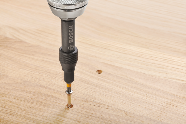 Drill driver making a hole in a wooden surface.