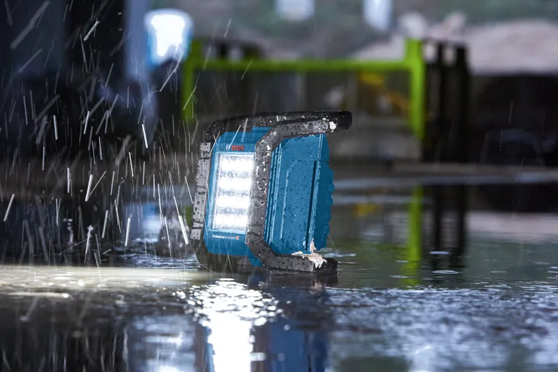 Work light operating on a wet floor during heavy rain at a construction site.