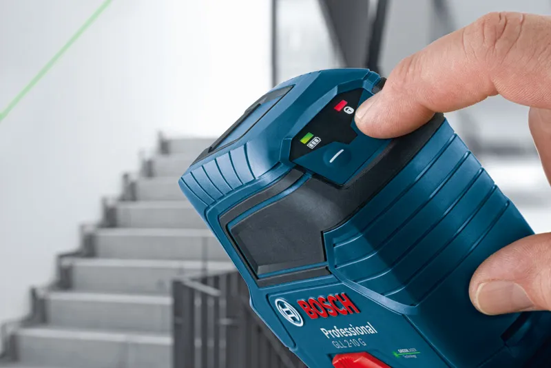 Person adjusts a laser leveling tool projecting a green line across a stairway.