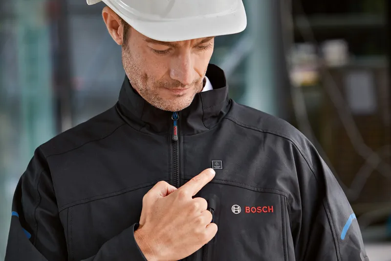 Person wearing safety equipment activates a heated jacket by pressing the chest button.
