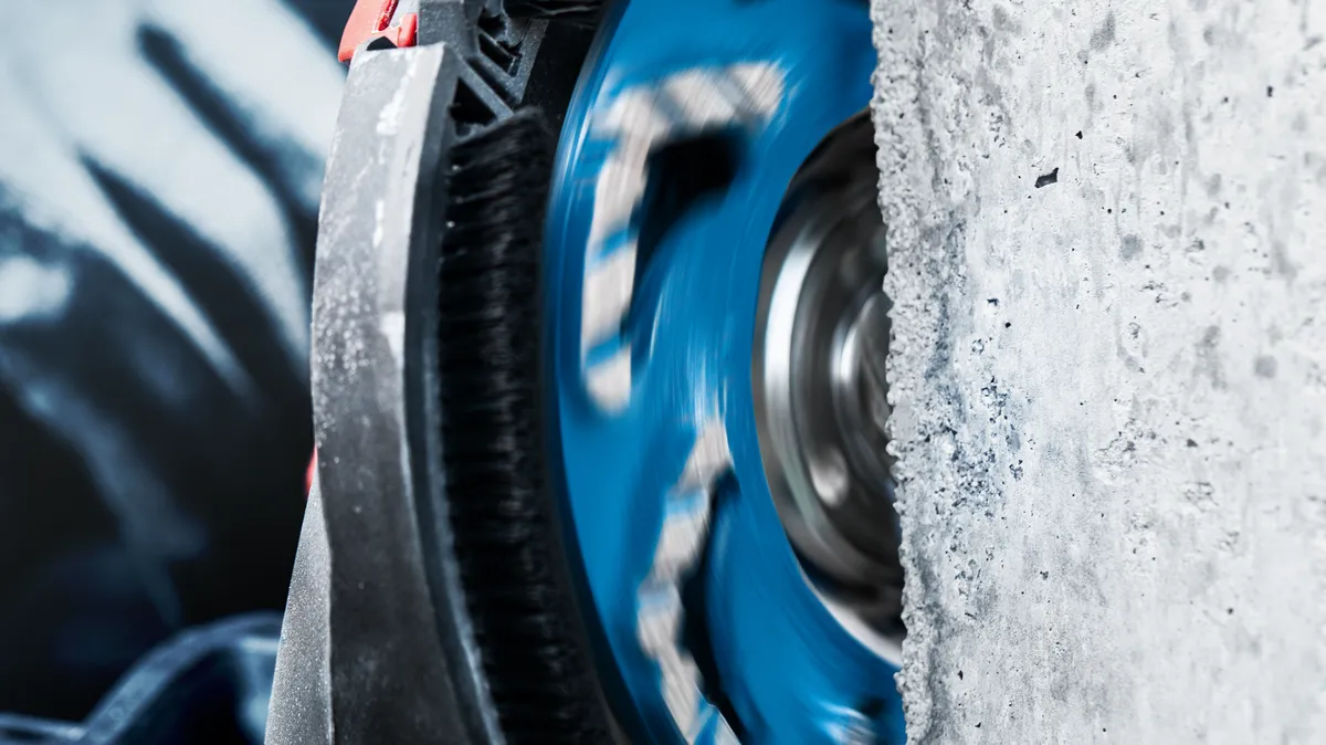 Rotating diamond blade cutting through concrete wall.