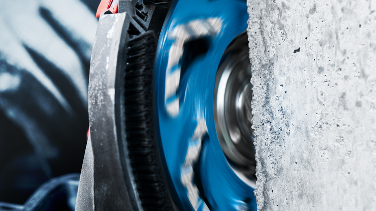 Rotating diamond blade cutting through concrete wall.