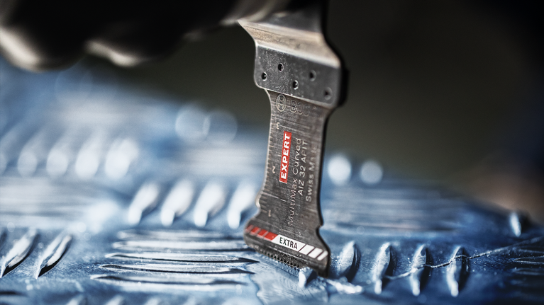 Saw blade cutting into a textured metal surface.