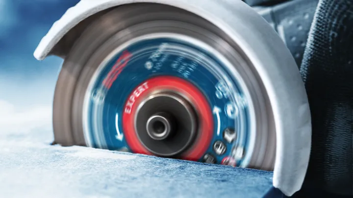 Rotary saw blade cutting through a slab of tile.