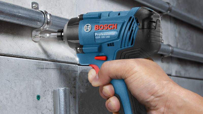 A person operates an impact wrench to fasten a bolt onto a metal pipe.