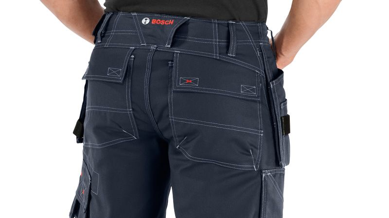 A person wearing blue work shorts with holster pockets and reinforced stitching.