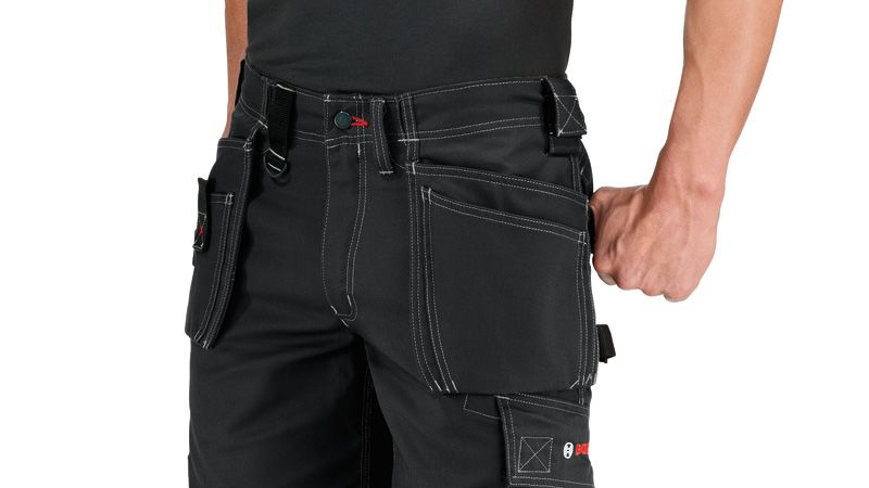 A person stands wearing blue work shorts with holster pockets and visible stitching.