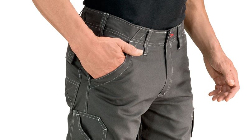 Person wearing grey trousers with knee pockets, one hand in pocket.