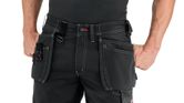 A person wearing black shorts with holster pockets stands with hands in pockets.