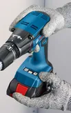 A person wearing safety equipment operates a cordless power drill.
