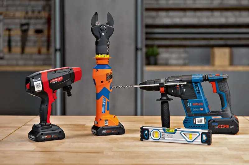 Cordless power tools and a leveling tool arranged on a wooden workbench.
