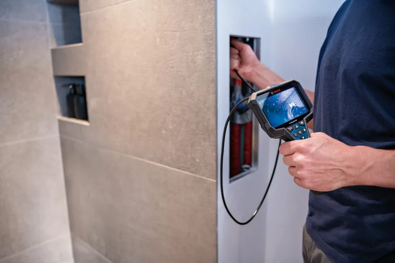 Person uses an inspection camera to examine inside a wall panel.