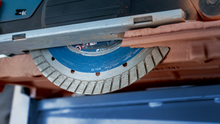 Diamond saw blade cutting through a brown brick.