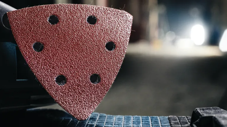Detail view of a triangular sanding pad attached to a power tool.