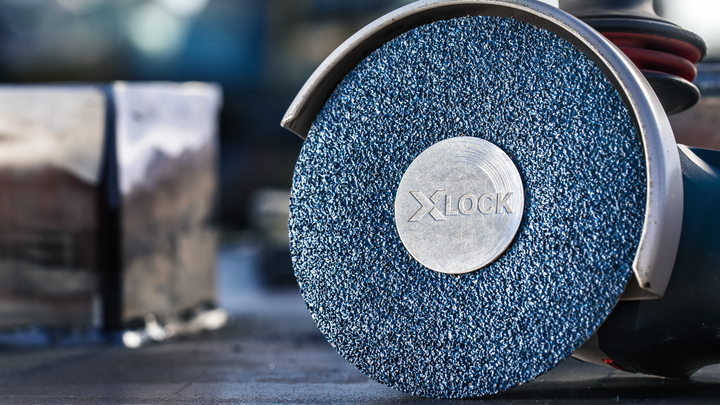 Close-up of an angle grinder with an abrasive disc placed on a workbench.