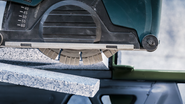 Circular saw cuts through thick granite slab.