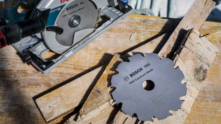 Circular saw and separate saw blade placed on wooden planks.