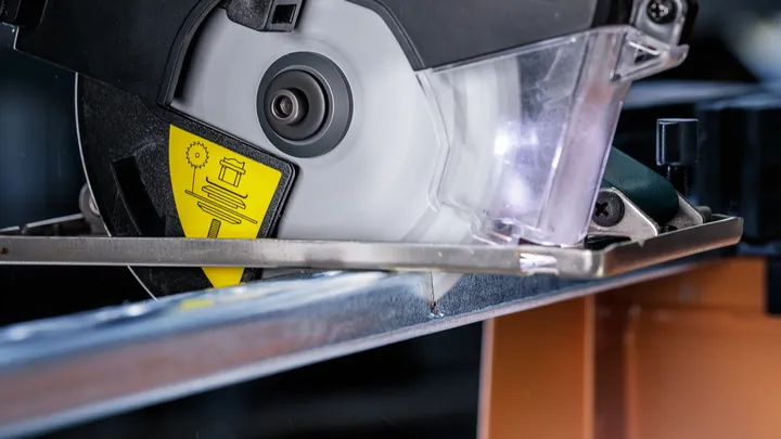 Circular saw cutting through a metal beam in a workshop.