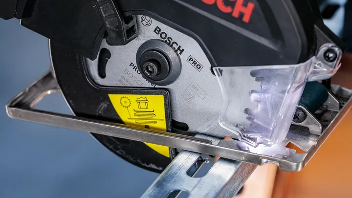 Power saw cutting through a metal beam with protective shield in place.