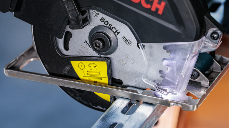 Power saw cutting through a metal beam with protective shield in place.