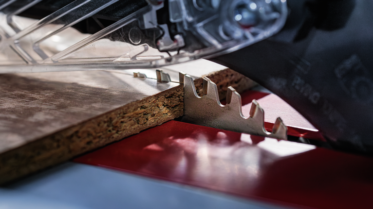 Circular saw cutting through a piece of particle board.