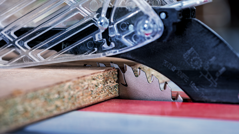Circular saw blade cutting through a wooden board.
