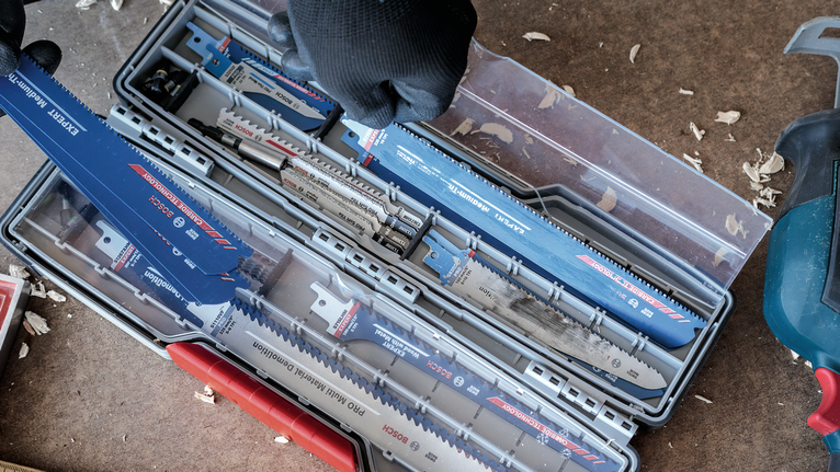 Person wearing safety equipment organizes saw blades in a storage case.