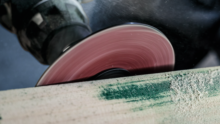 Rotating circular saw blade cutting through a wooden plank.