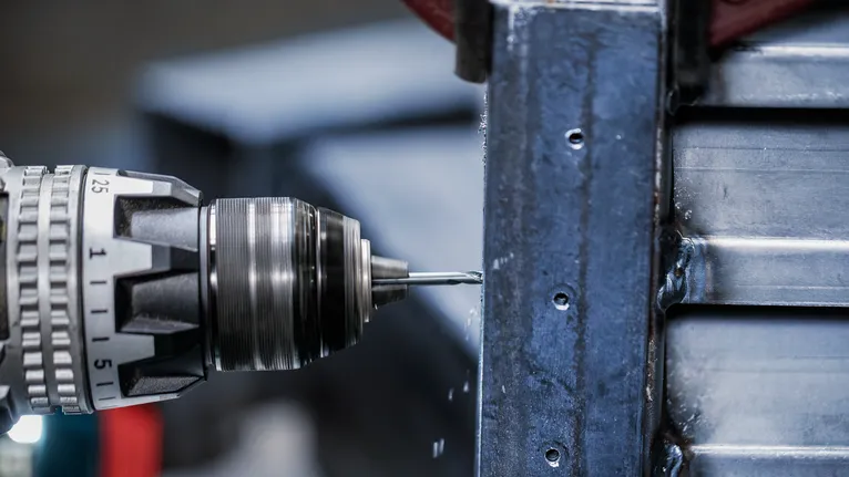 Drill making holes in a metal beam.