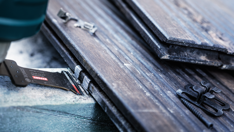 Oscillating multi-tool cuts through laminate flooring, screws and clips nearby.