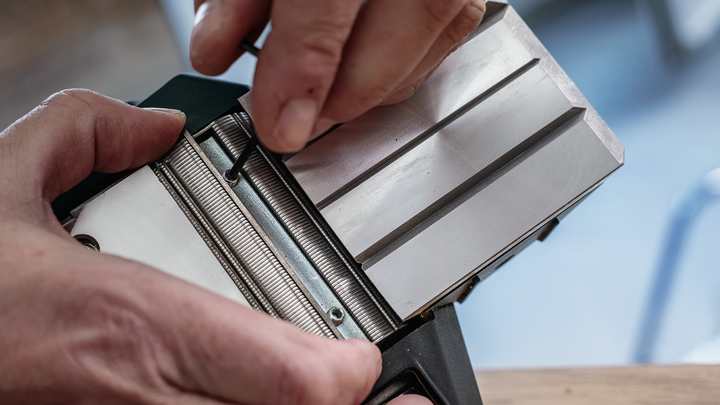 Person adjusts a metal tool component using a hex key.