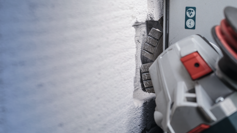 Wall chaser cutting a straight groove into a concrete wall.